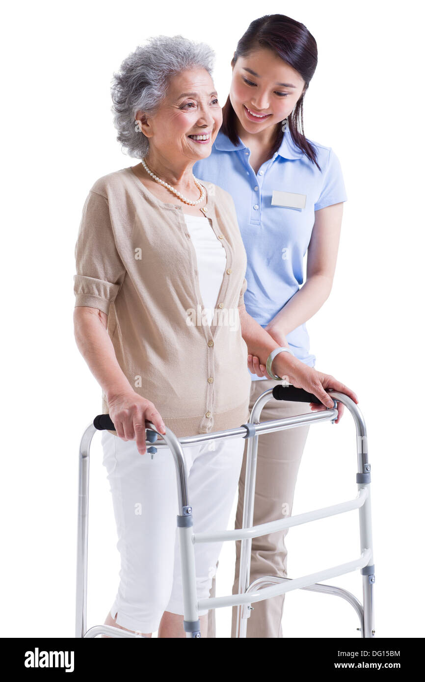 Female nursing assistant helping senior woman with walking frame Stock ...