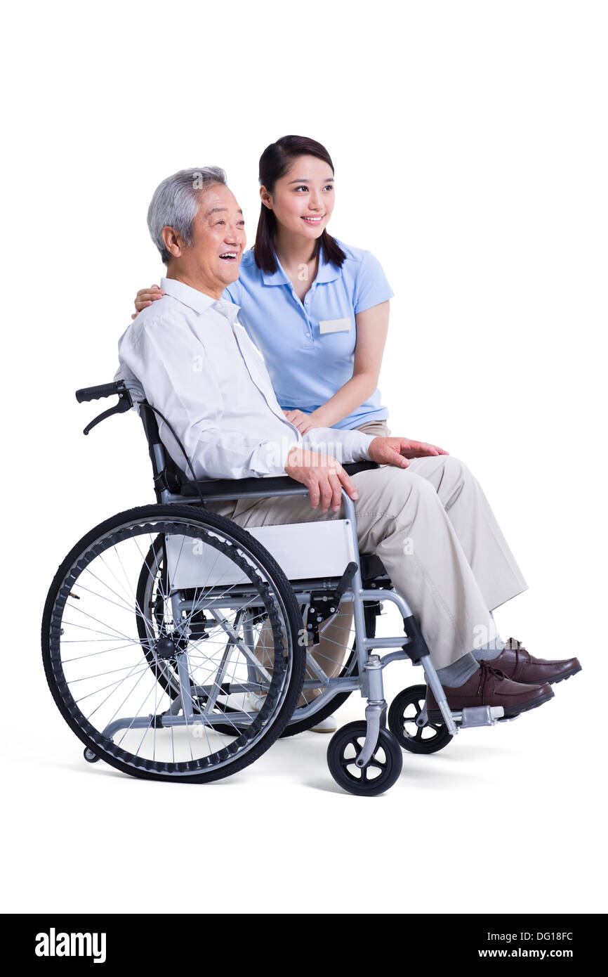 Female nursing assistant taking care of senior in wheelchair Stock