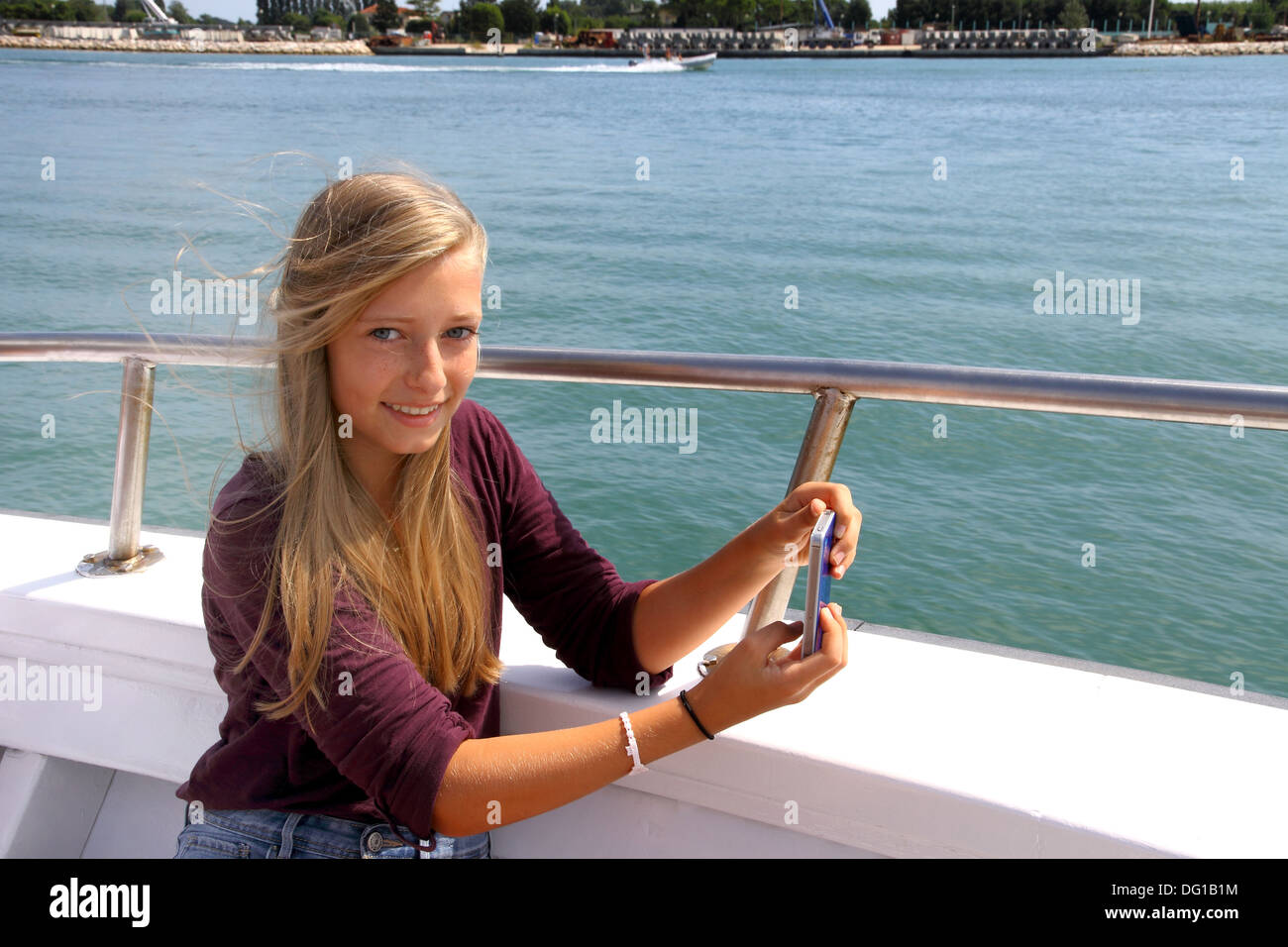 Happy blond girl with phone on the ship, horizontal Stock Photo