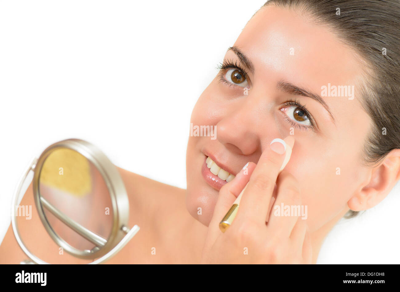 Young woman using concealer looking in the mirror Stock Photo