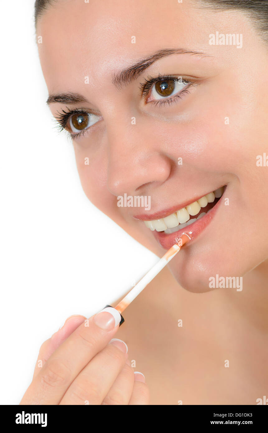 Young beautiful woman applying lipgloss on her lips Stock Photo