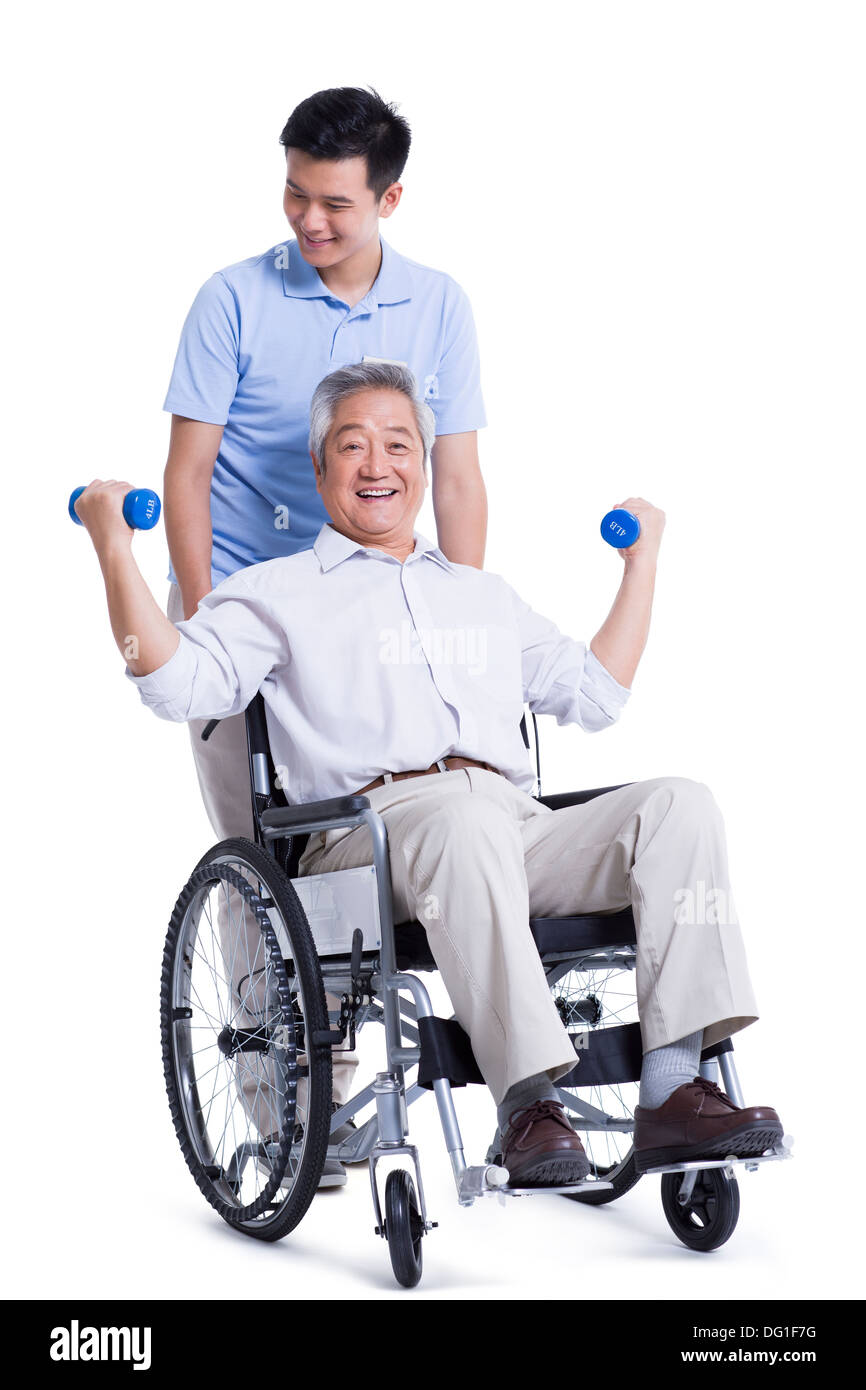 Male nursing worker helping senior man doing exercise Stock Photo