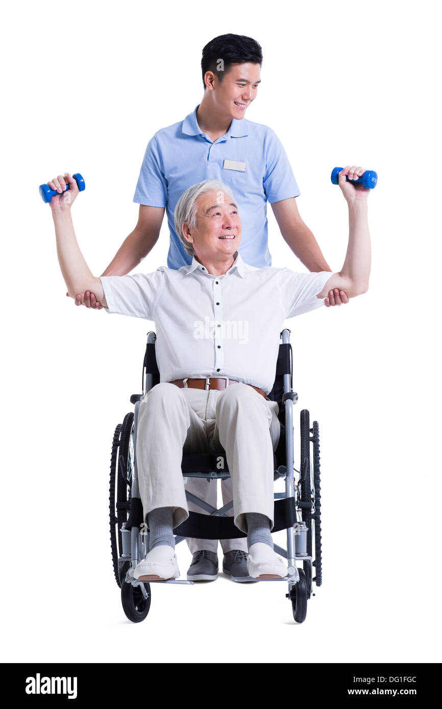 Male nursing worker helping senior man doing exercise Stock Photo