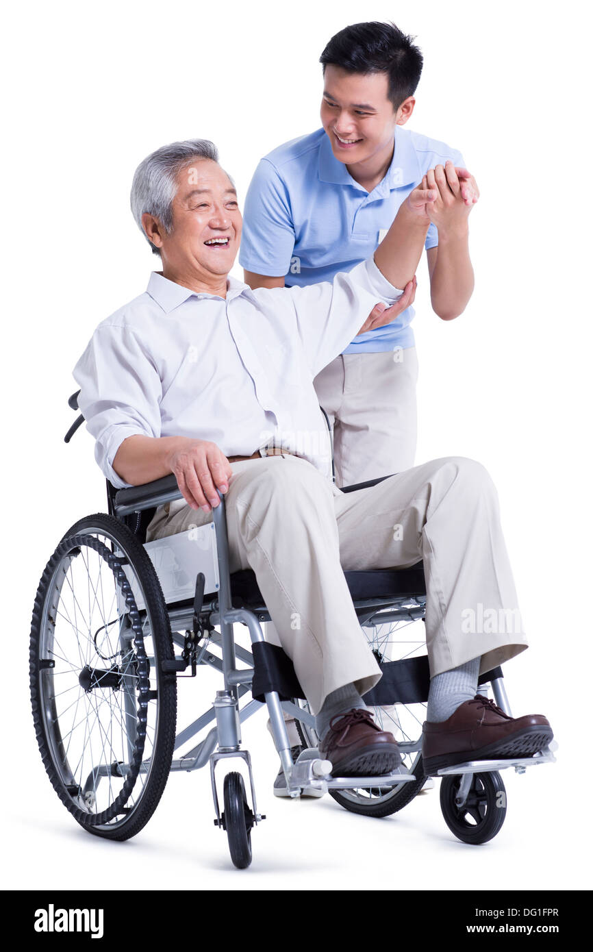 Male nursing worker helping senior man doing exercise Stock Photo