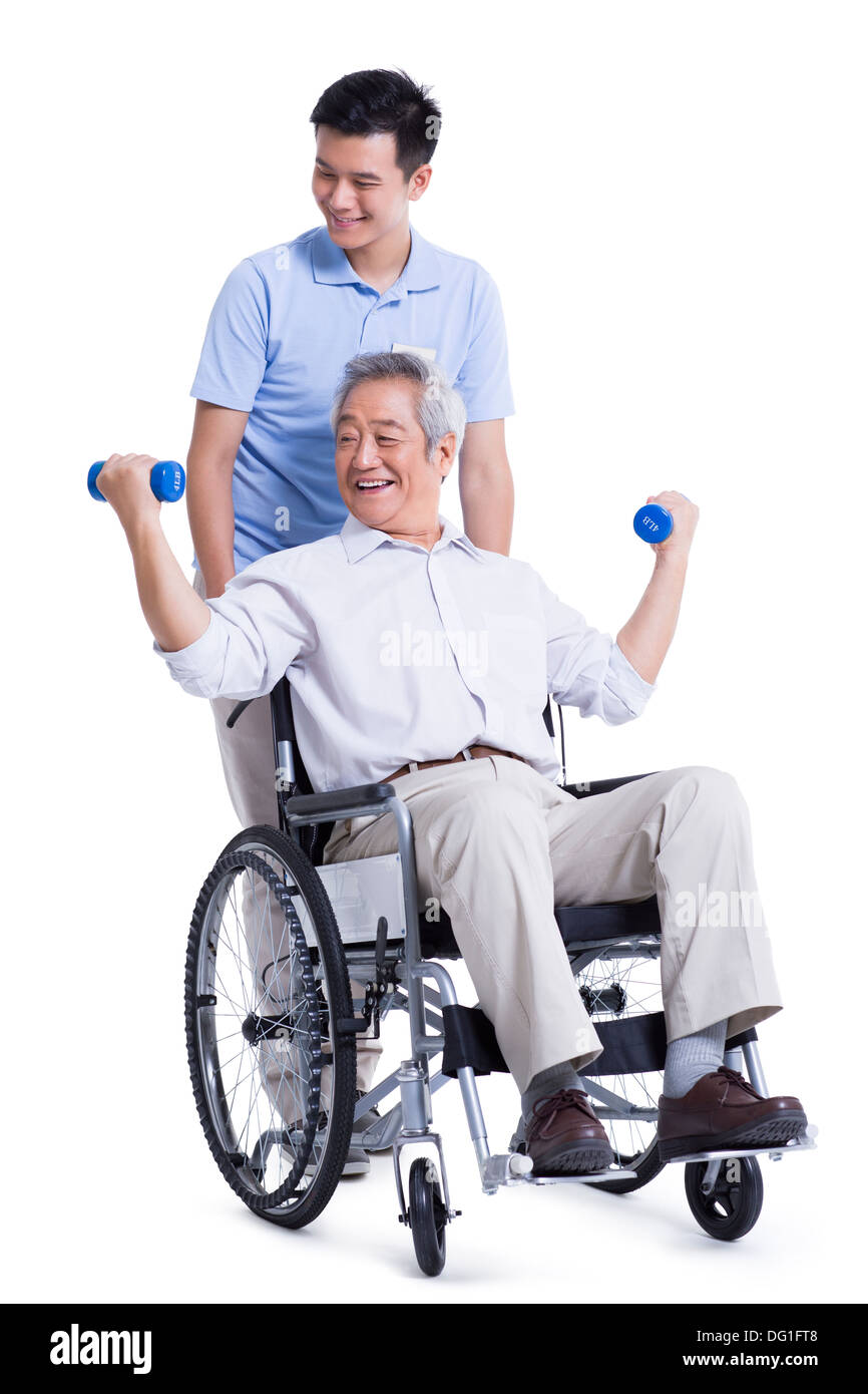 Male nursing worker helping senior man doing exercise Stock Photo