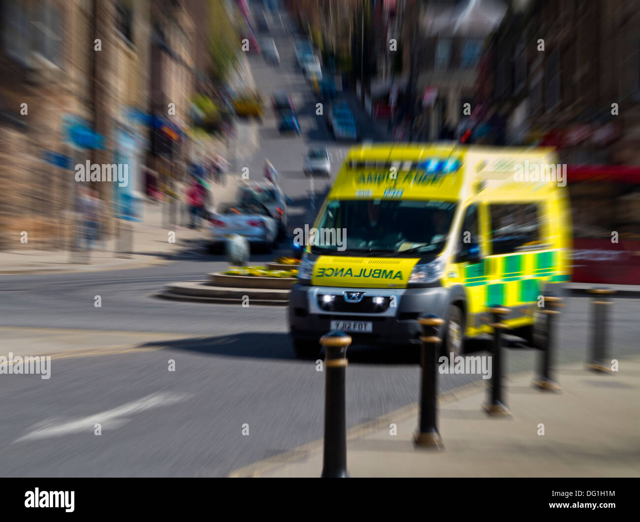 NHS Emergency Ambulance rushing through a British town centre with motion blur Stock Photo