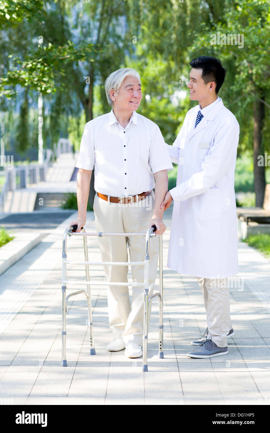 Senior man walking with walking frame under doctor's assistance Stock Photo