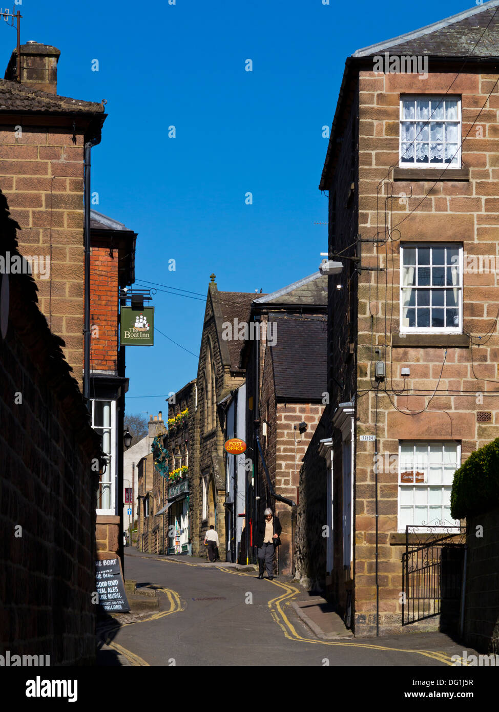 View of lane in Cromford village Derbyshire Dales Peak District England UK looking towards post office and Scarthin Books shop Stock Photo