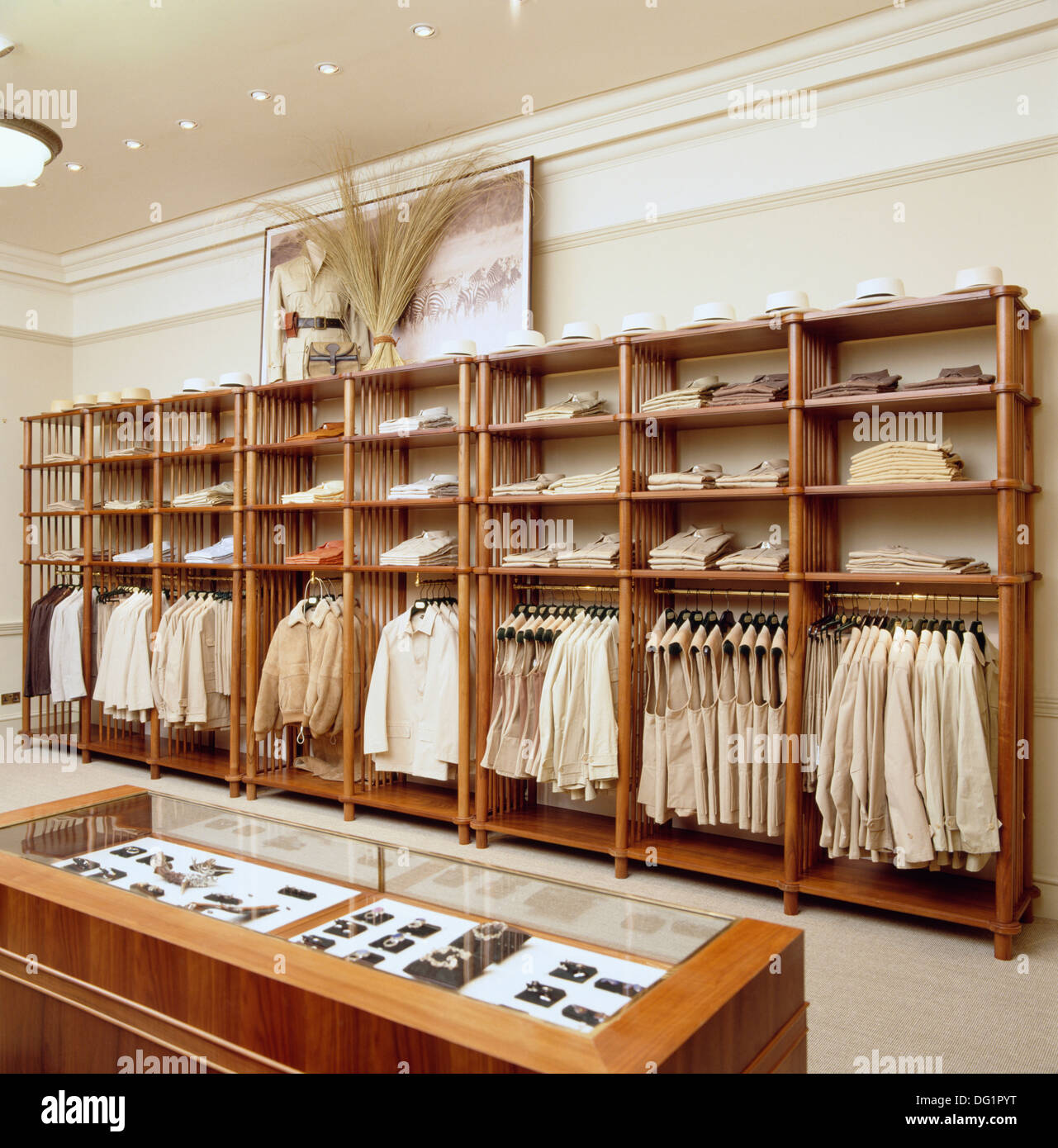 Upmarket men's clothing shop with cream shirts and jackets hanging on rails  below display shelves Stock Photo - Alamy
