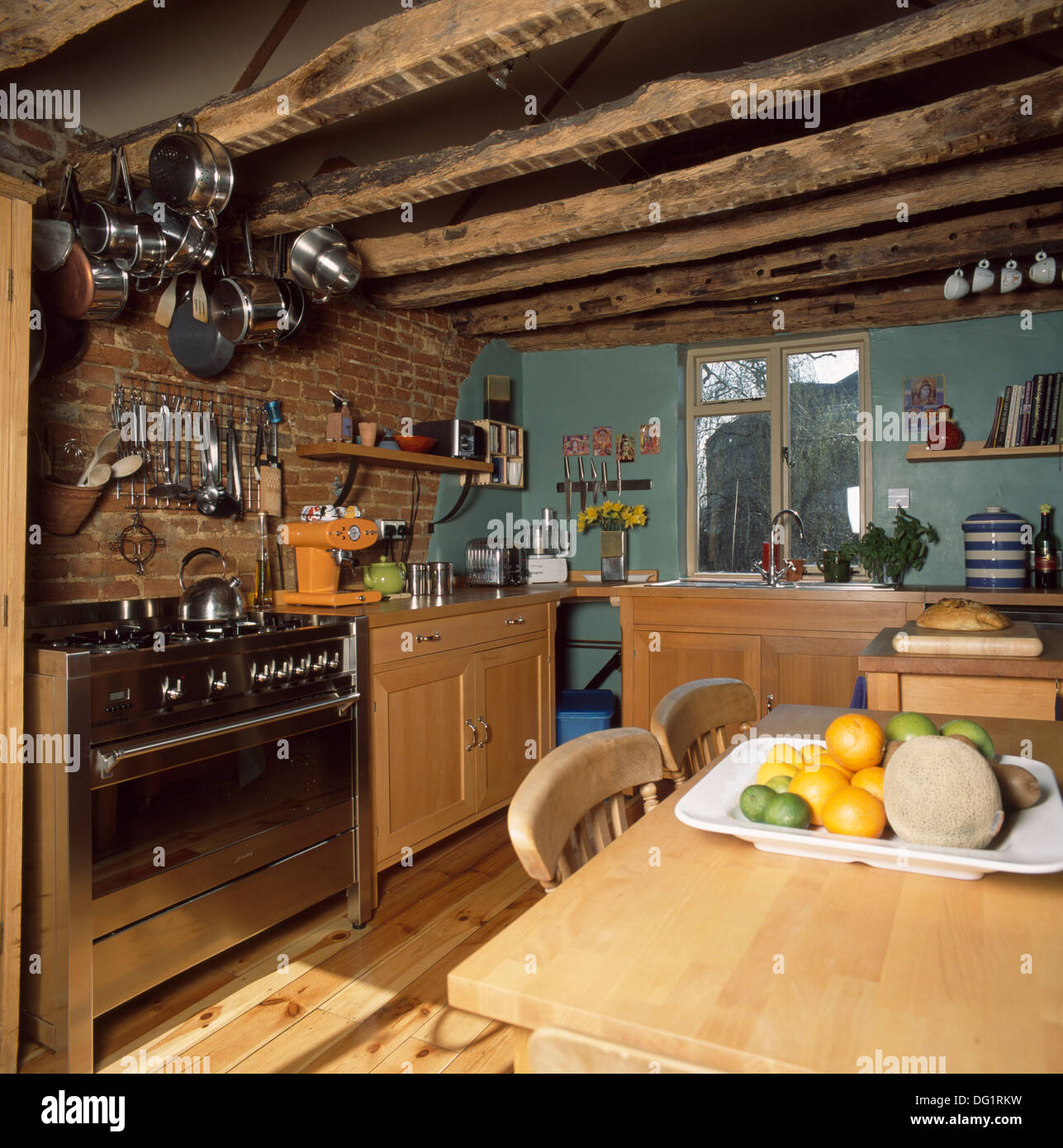 Pans on rack above stainless steel range oven in country kitchen with rustic wooden beams and