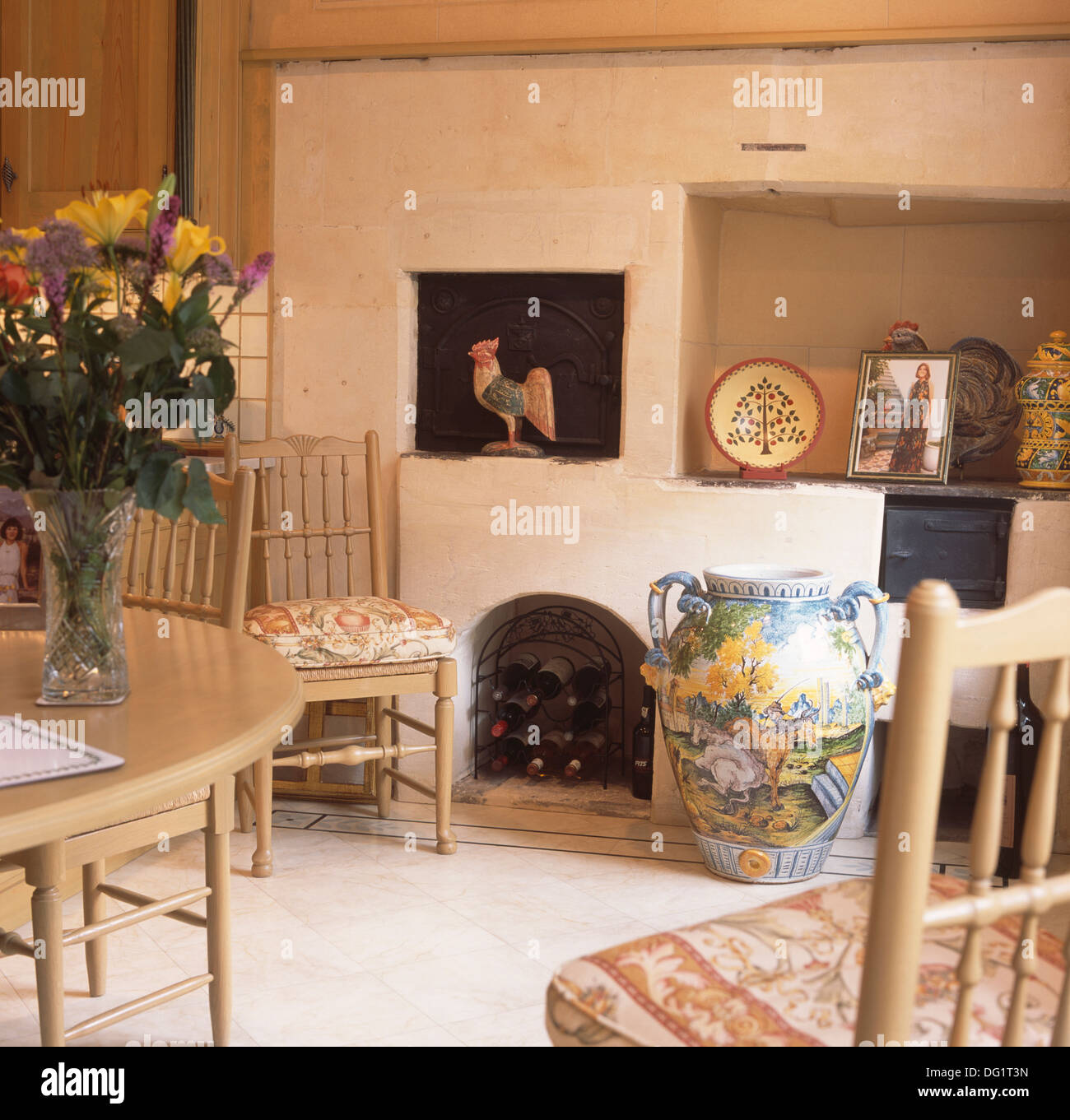 Large pictorial pottery jar beside wine storage in fireplace below old
