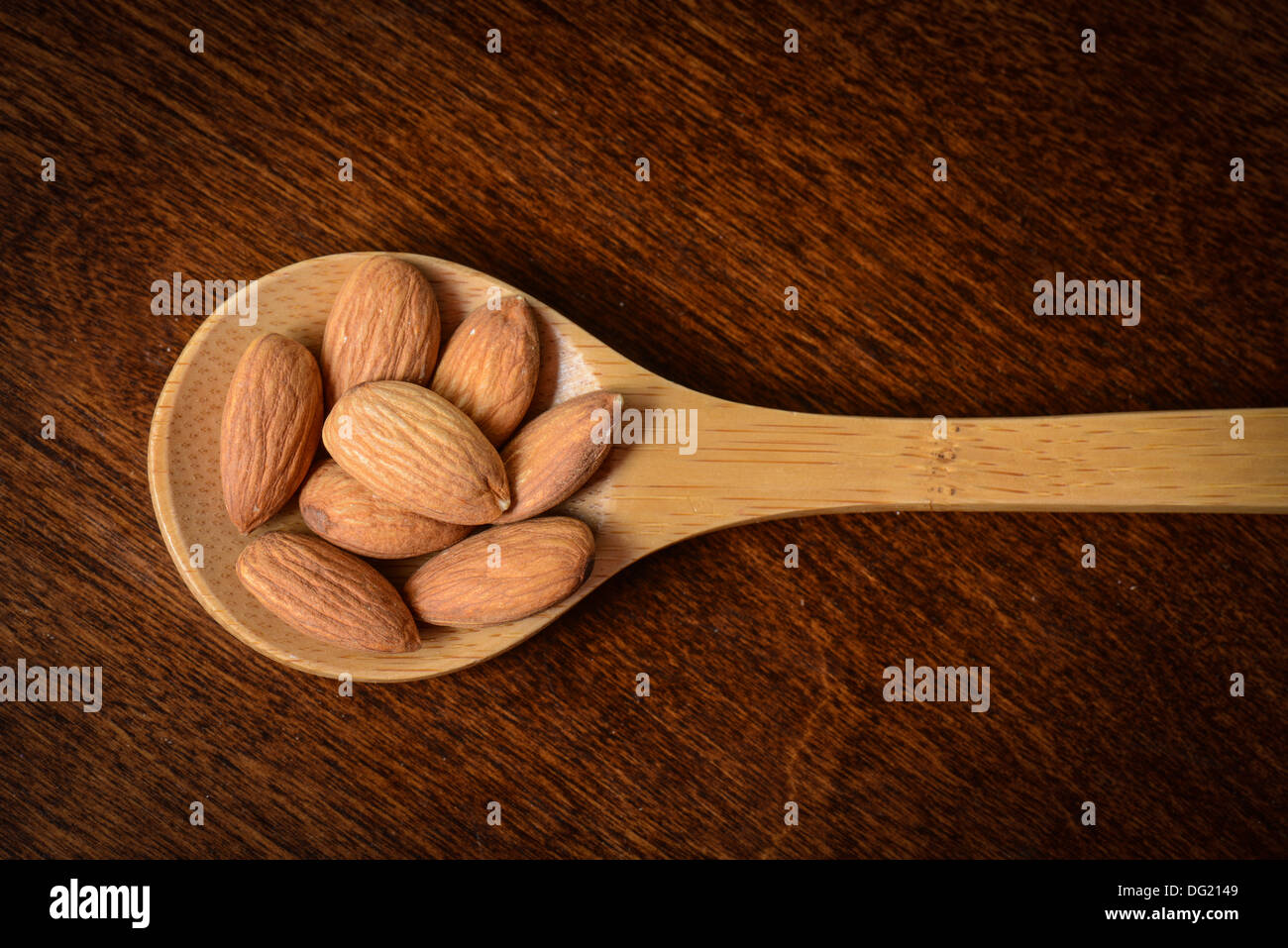 Almonds on a Wooden Spoon with Wood Texture Background Stock Photo