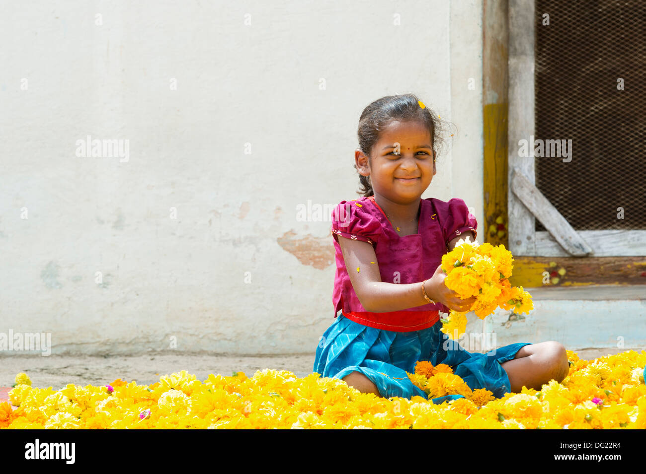 Rural indian village girl sitting holding marigold flowerheads. Andhra Pradesh, India Stock Photo