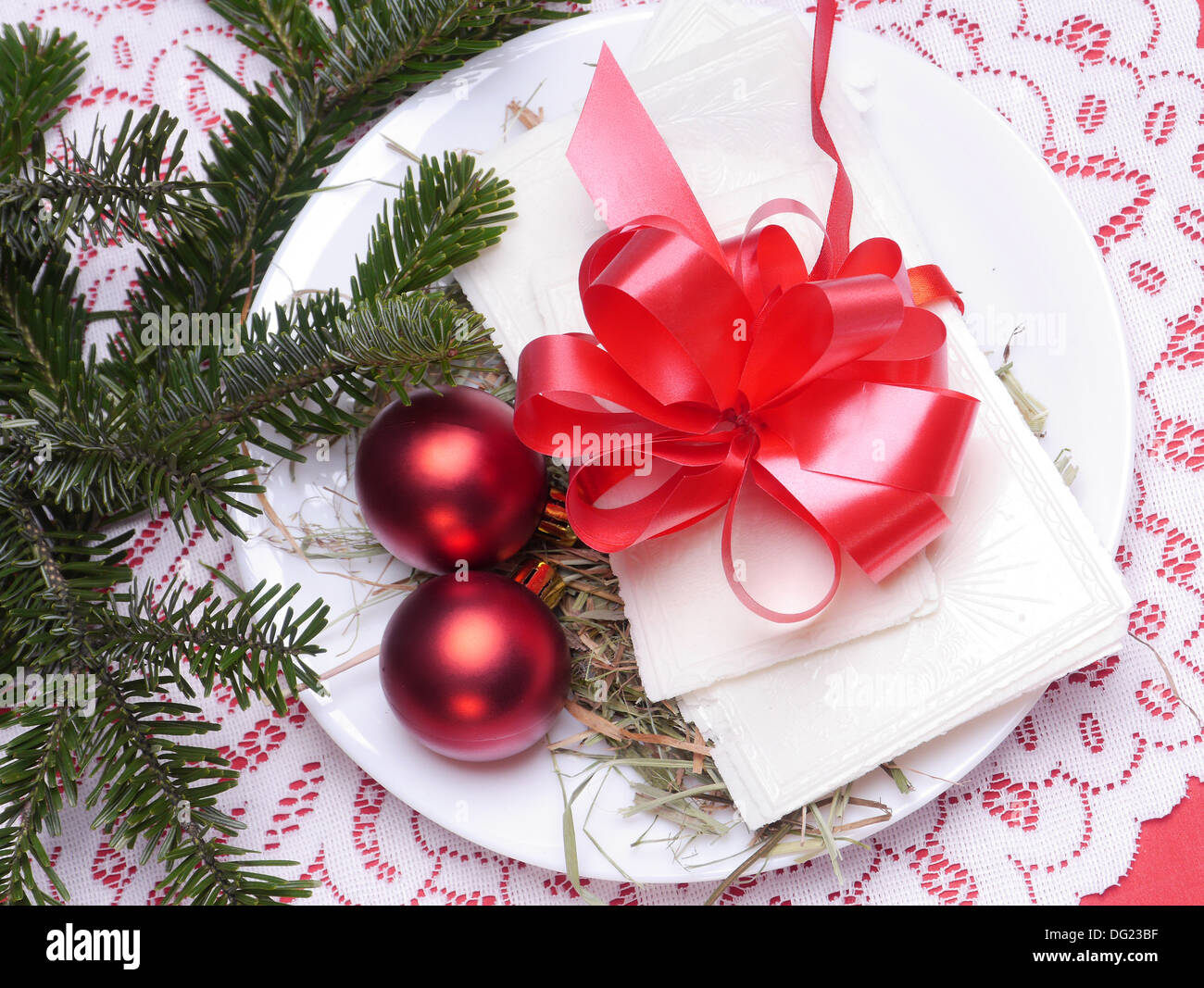 Traditional Christmas Eve white wafer on a plate with red christmas balls Stock Photo