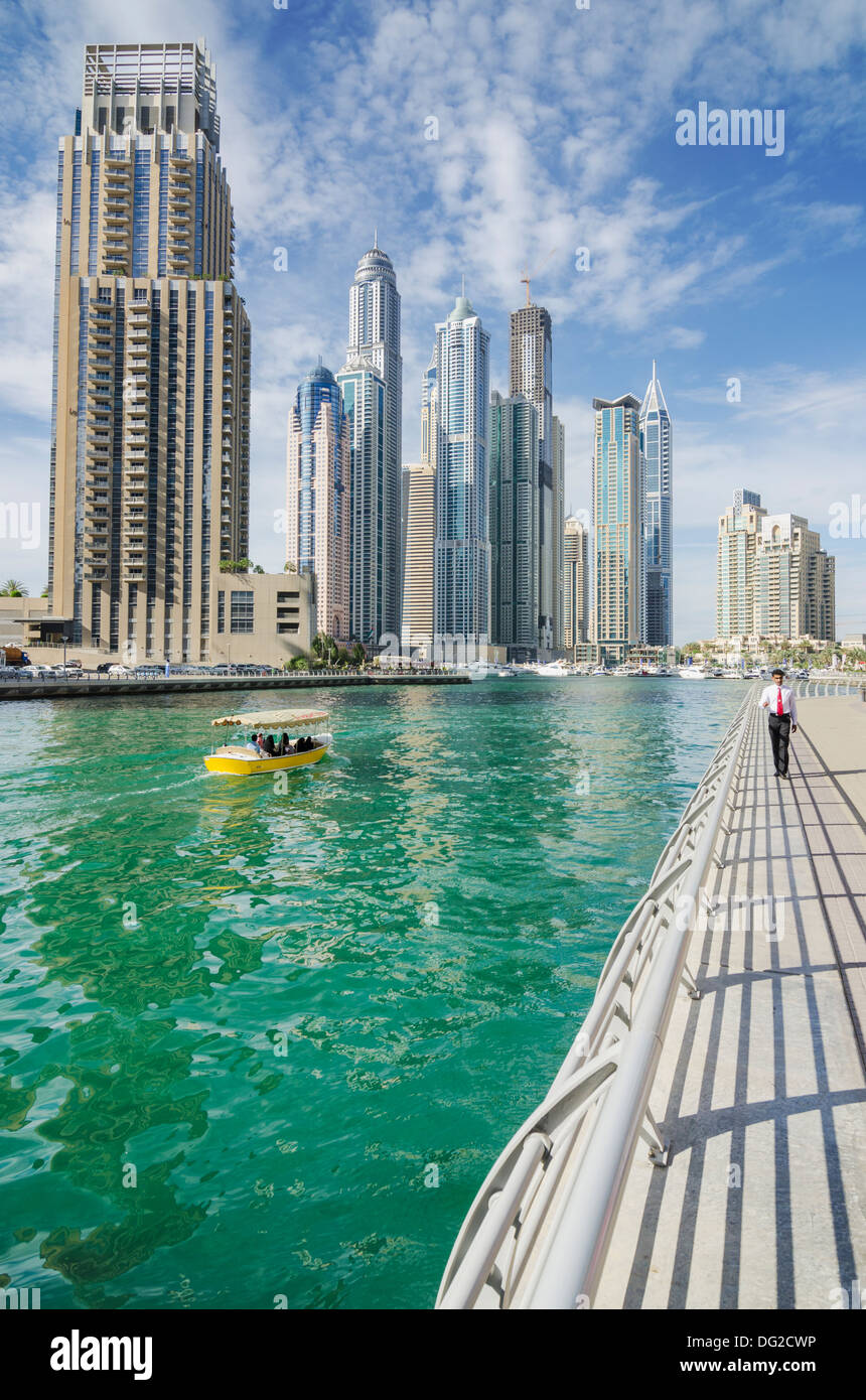 A taxi boat and business man walking along Dubai Marina promenade, Dubai, UAE Stock Photo