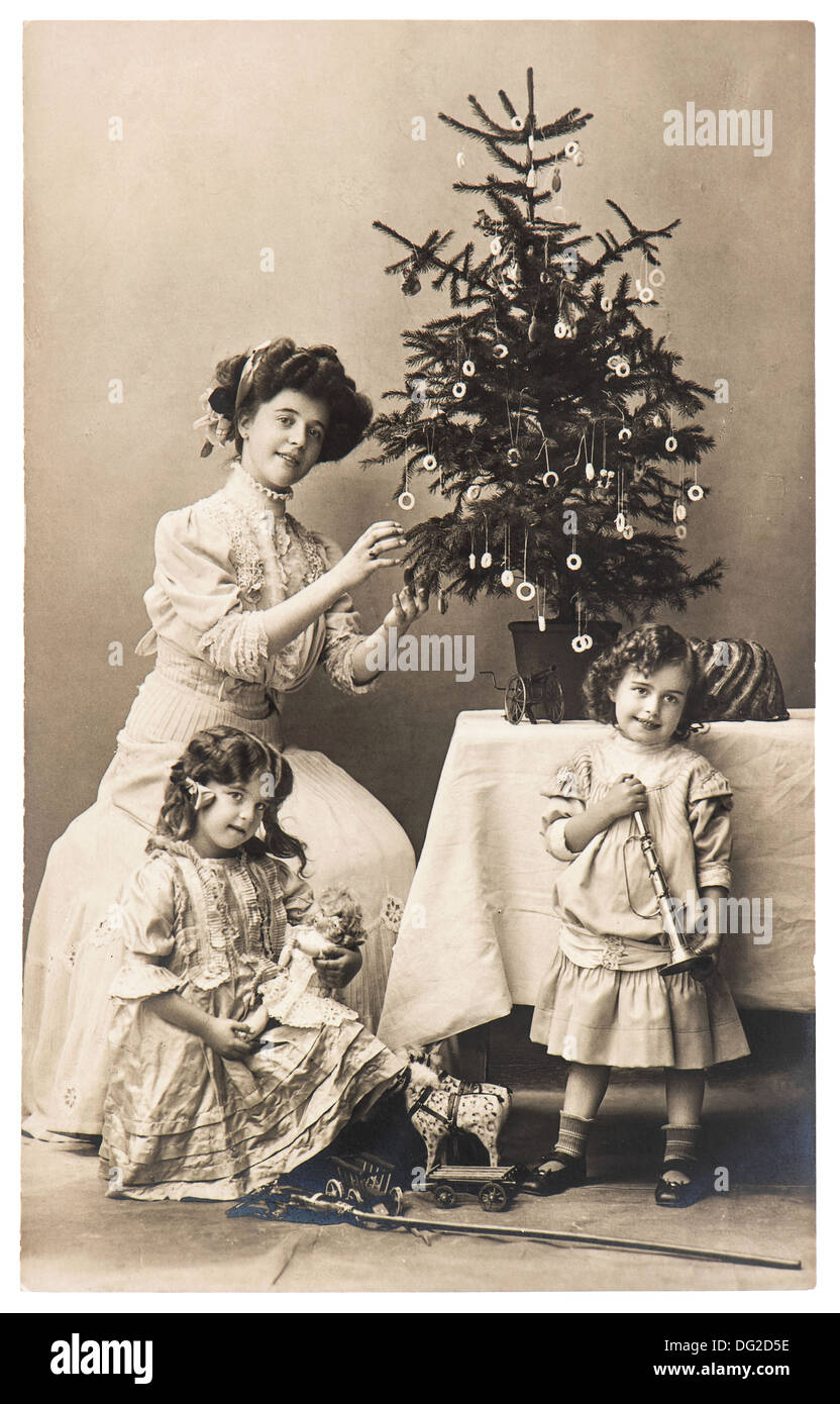 antique family portrait of mother and children with christmas tree wearing vintage clothing Stock Photo