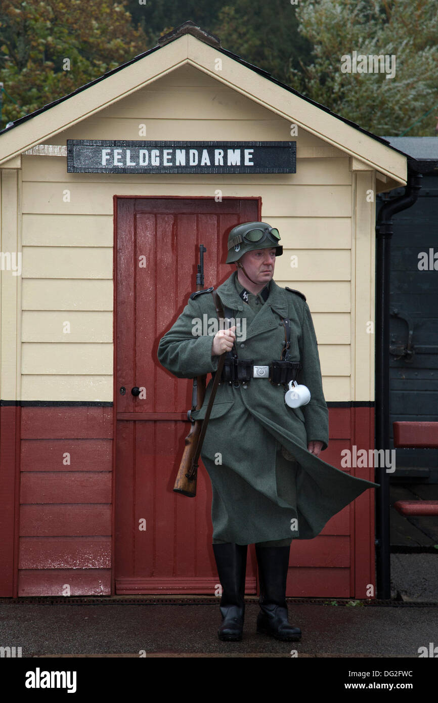 1940 Wartime Sentry. A  reenactor army man in tin hat at Levisham. North Yorkshire, UK.  11th October, 2013. Feldgendarmerie at the ‘Railway in Wartime’  North Yorks Moors Railway (NYMR) event at Levisham Railway Station in inclement weather on weekend 12th-13th October 2013.   Levisham Station, was decorated with period posters, and French signs  during the (NYMR) ‘Wartime Weekend’ to become  ‘Le Visham’ in northern France. The gathering, a recreation of a French village occupied by World War Two, World War II, Second World War,  WWII, WW2 German troops, Stock Photo
