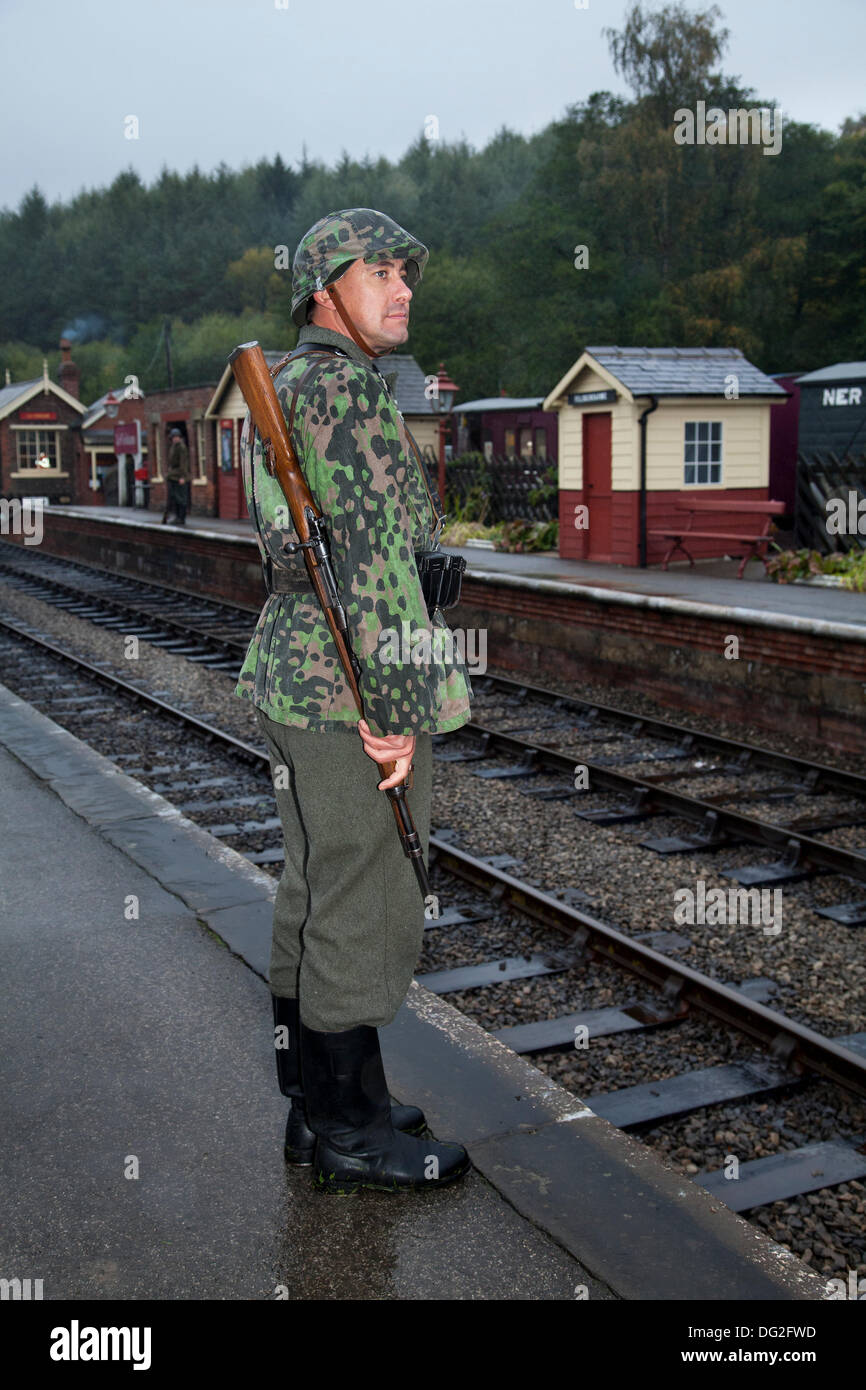 1940 Wartime army man at Levisham. North Yorkshire, UK.  11th October, 2013. Feldgendarmerie at the ‘Railway in Wartime’  North Yorks Moors Railway (NYMR) event at Levisham Railway Station in inclement weather on weekend 12th-13th October 2013.   Levisham Station, was decorated with period posters, and French signs  during the (NYMR) ‘Wartime Weekend’ to become  ‘Le Visham’ in northern France. The gathering, a recreation of a French village occupied by World War Two, World War II, Second World War,  WWII, WW2 German troops. Stock Photo