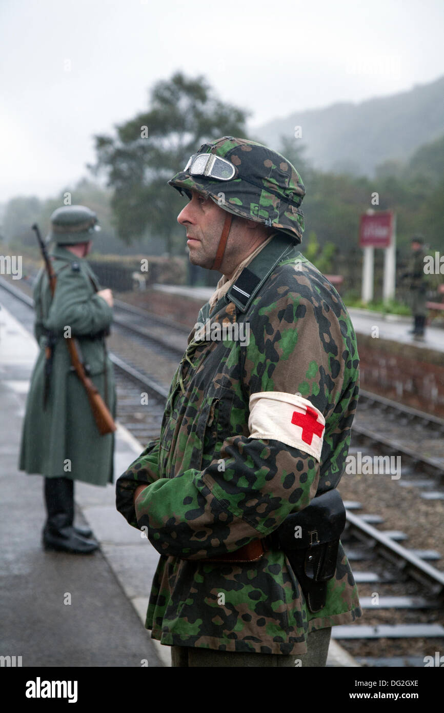 1940 Wartime army man at Levisham. North Yorkshire, UK.  11th October, 2013. German Station guards or Feldgendarmerie at the ‘Railway in Wartime’  North Yorks Moors Railway (NYMR) event at Levisham Railway Station in inclement weather on weekend 12th-13th October 2013.   Levisham Station, was decorated with period posters, and French signs  during the (NYMR) ‘Wartime Weekend’ to become  ‘Le Visham’ in northern France. The gathering, a recreation of a French village occupied by German troops, being part of the ‘Allo Allo’-style light-hearted and fun mood. Stock Photo