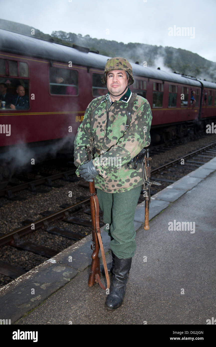 1940 Wartime army man at Levisham. North Yorkshire, UK.  11th October, 2013. Kevin Armstrong from London as a SS Waffen German soldier at the  ‘Railway in Wartime’  North Yorks Moors Railway (NYMR) event at Levisham Railway Station in inclement weather on weekend 12th-13th October 2013.   Levisham Station, was decorated with period posters, and French signs  during the (NYMR) ‘Wartime Weekend’ to become  ‘Le Visham’ in northern France. The gathering, a recreation of a French village occupied by World War Two, World War II, Second World War,  WWII, WW2 German troops, Stock Photo