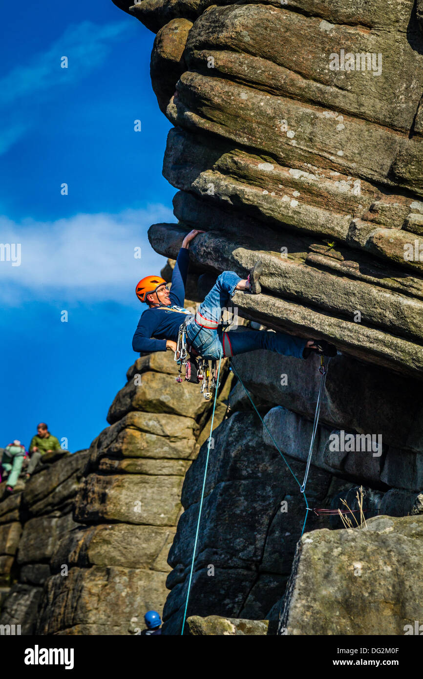 Male rock climber person doing a Heel hook on the crux of Flying Buttress Direct, Stanage, Peak District, UK Stock Photo