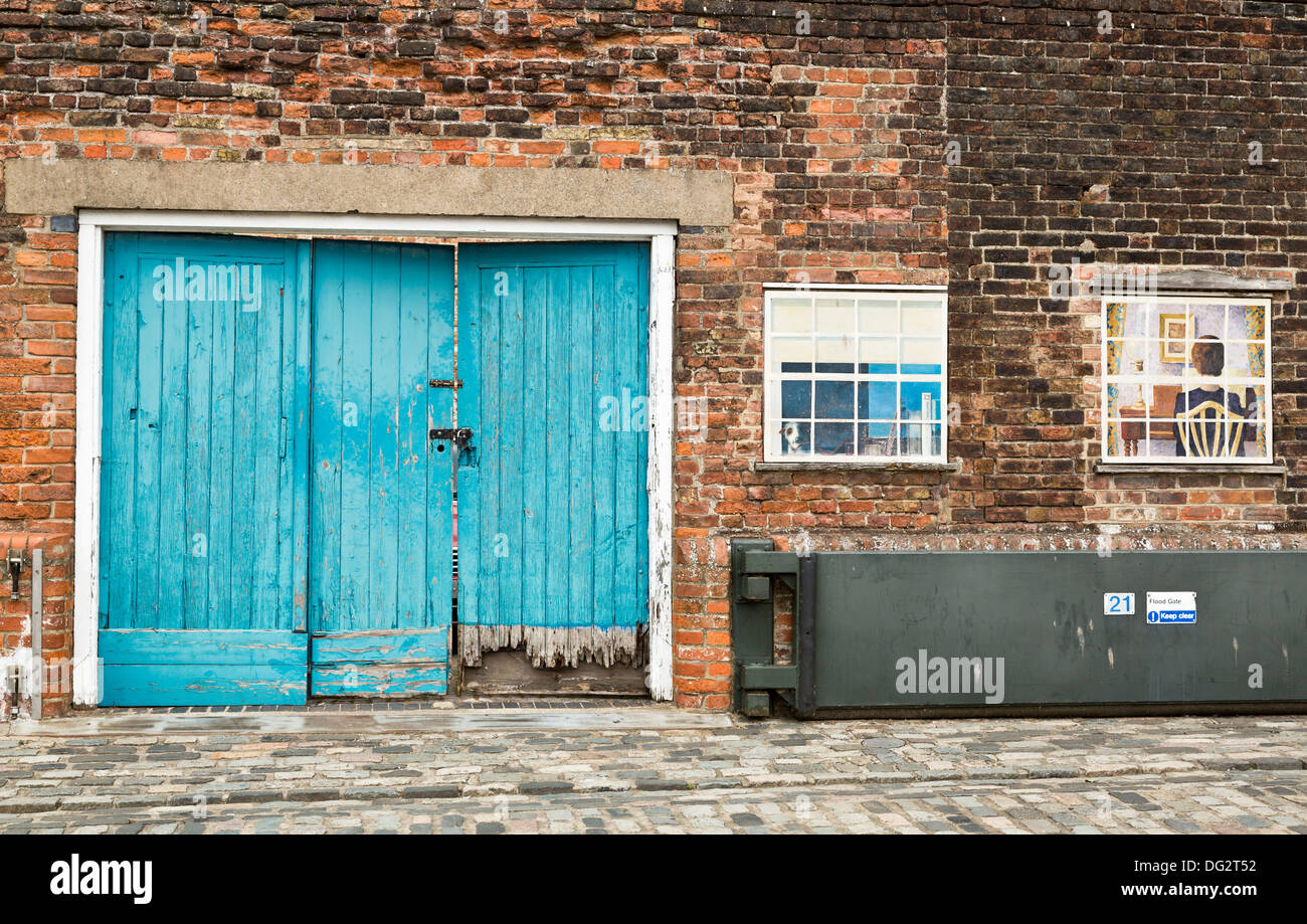 Flood gate next to old water damaged wooden door in King's Lynn