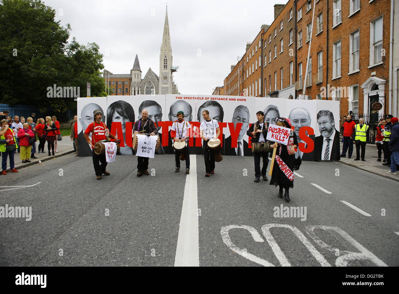 Dublin, Ireland. 12th October 2013. Members of the Spectacle of Defiance & Hope hold large signs with pictures of government ministers and reads 'Austerity Kills'. Members with drums walk in front of the sign. Unions called for a protest march through Dublin, ahead of the announcing of the 2014 budget next week. They protested against cuts in Social Welfare, Health and Education and for an utilisation of alternative revenue sources by the government. © Michael Debets/Alamy Live News Stock Photo