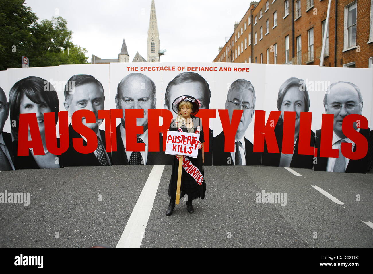 Dublin, Ireland. 12th October 2013. Members of the Spectacle of Defiance & Hope hold large signs with pictures of government ministers and reads 'Austerity Kills'. A female member walks in front of the signs. Unions called for a protest march through Dublin, ahead of the announcing of the 2014 budget next week. They protested against cuts in Social Welfare, Health and Education and for an utilisation of alternative revenue sources by the government. © Michael Debets/Alamy Live News Stock Photo