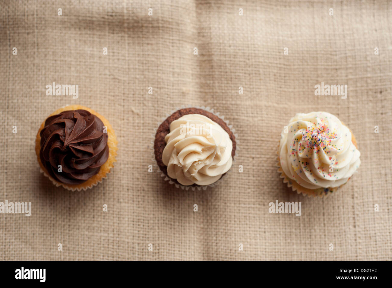 Three Cupcakes with Icing in Row, High Angle View Stock Photo