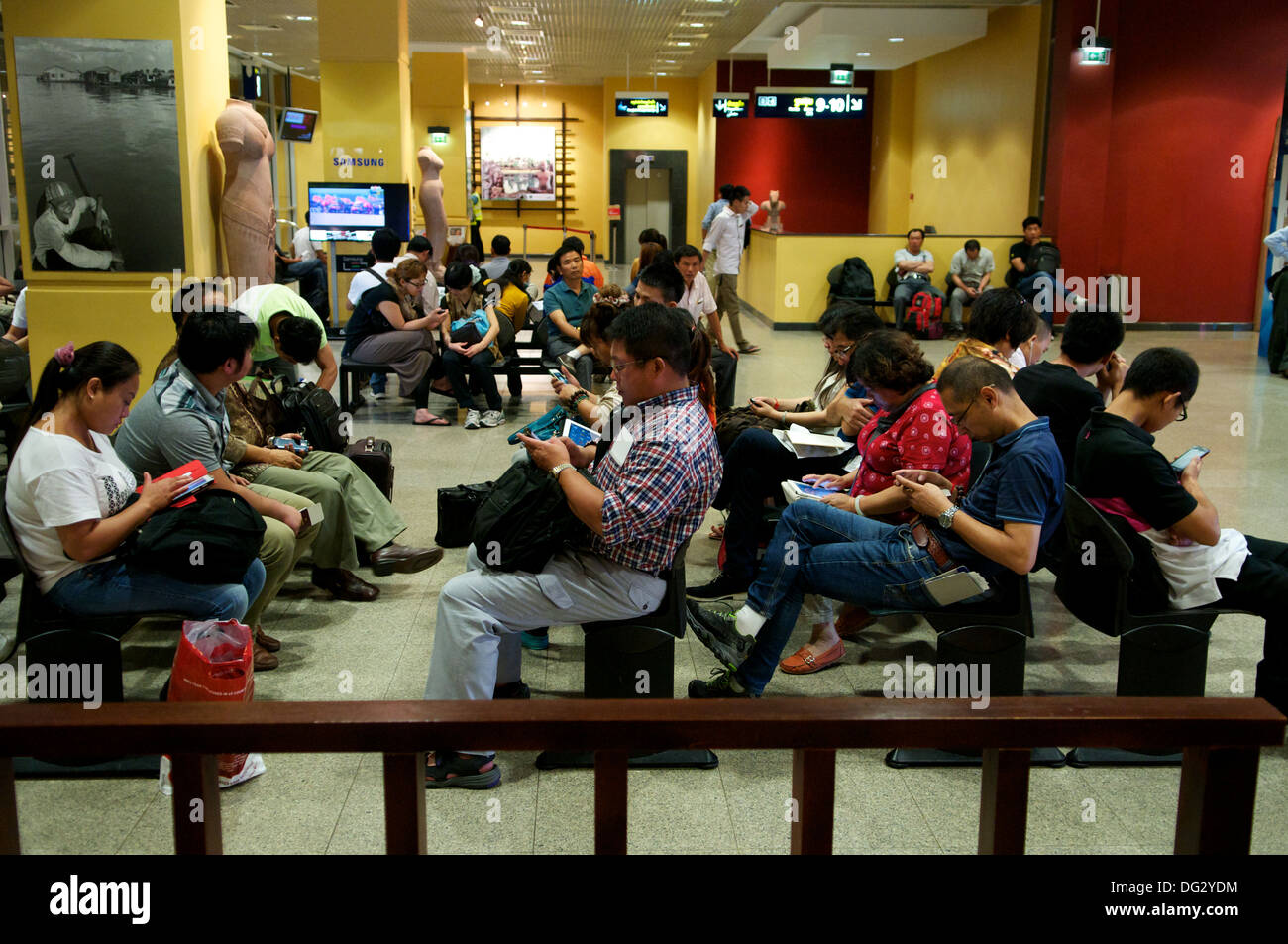 Chinese tourists overusing their gadgets at The Phnom Penh International Airport, Phnom Penh, Cambodia, Indochina. © Kraig Lieb Stock Photo