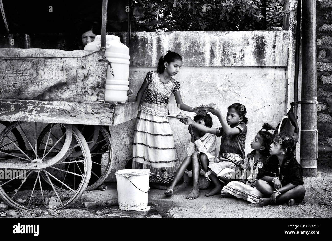 Indian lower caste children eating dosa for breakfast on an indian street. Andhra Pradesh, India. Monochrome Stock Photo