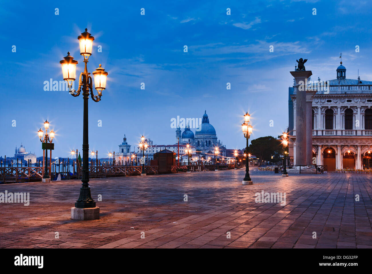 Italy Venice sunrise view on st marco square and Sana Maria Della Salute cathedral between illuminated street lamps Stock Photo