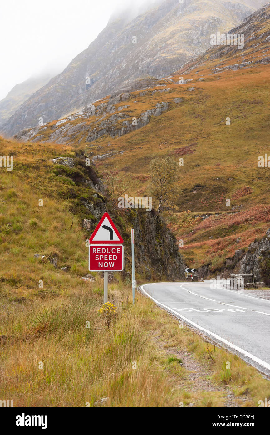The A 82 travelling trough Glencoe in the direction of fort william showing warning sign to reduce speed for sharp corner Stock Photo