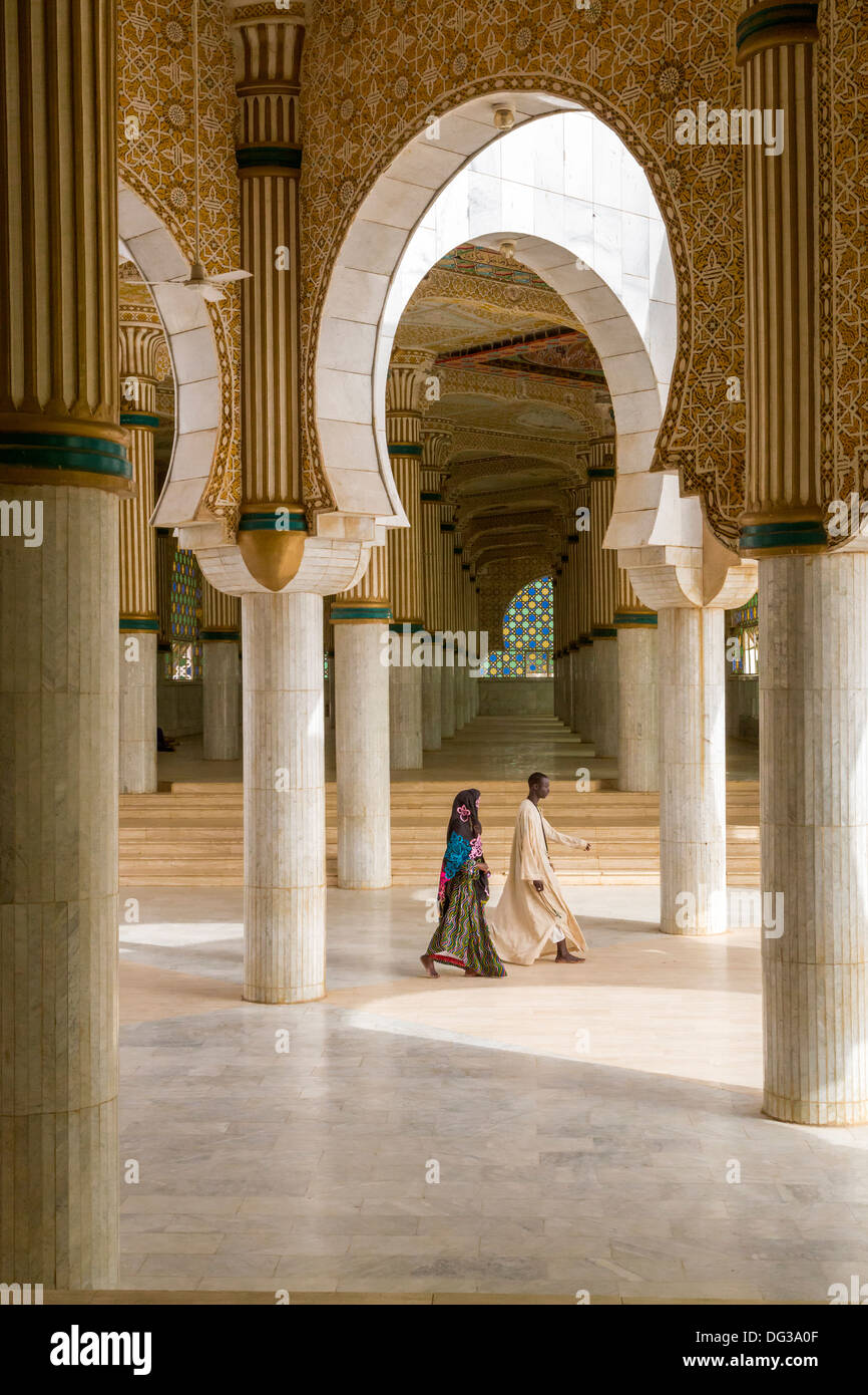 Senegal, Touba. Prayer Halls for Overflow Crowds at the Grand Mosque. Man and Woman Walking. Stock Photo