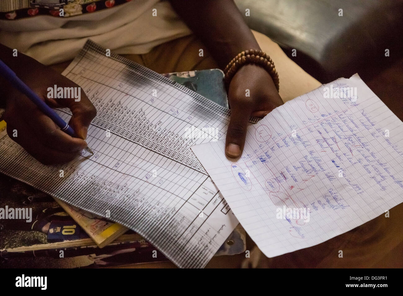 Senegal, Touba. Student Holding English Test Results, Entering Grade on Score Sheet. Stock Photo