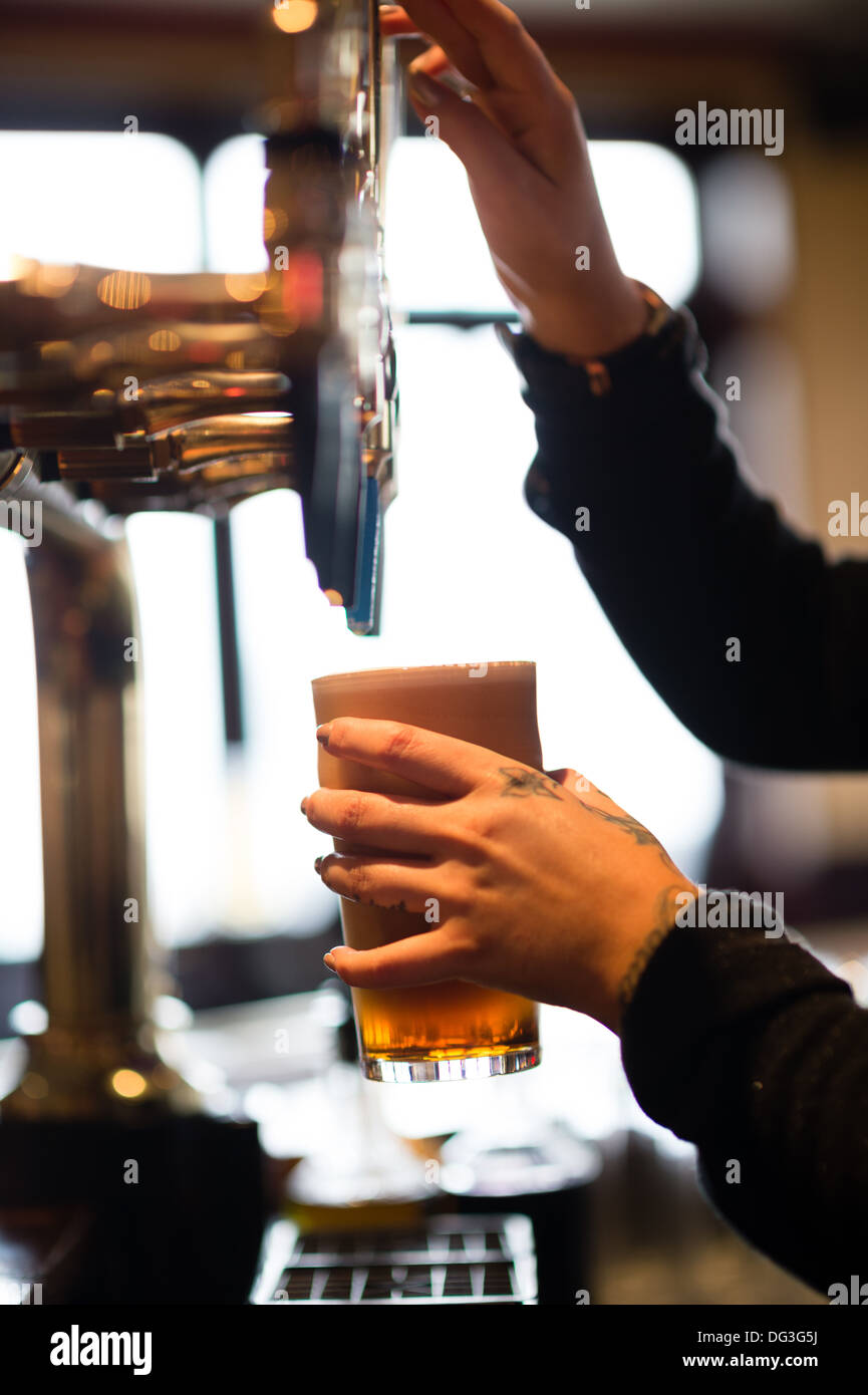 A young woman female bar worker pouring pulling a pint of beer in a pub inn UK Stock Photo Alamy