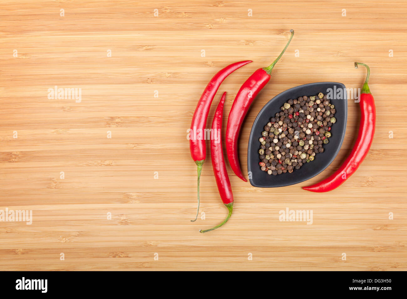 Red hot peppers and peppercorn on cutting board with copy space Stock ...