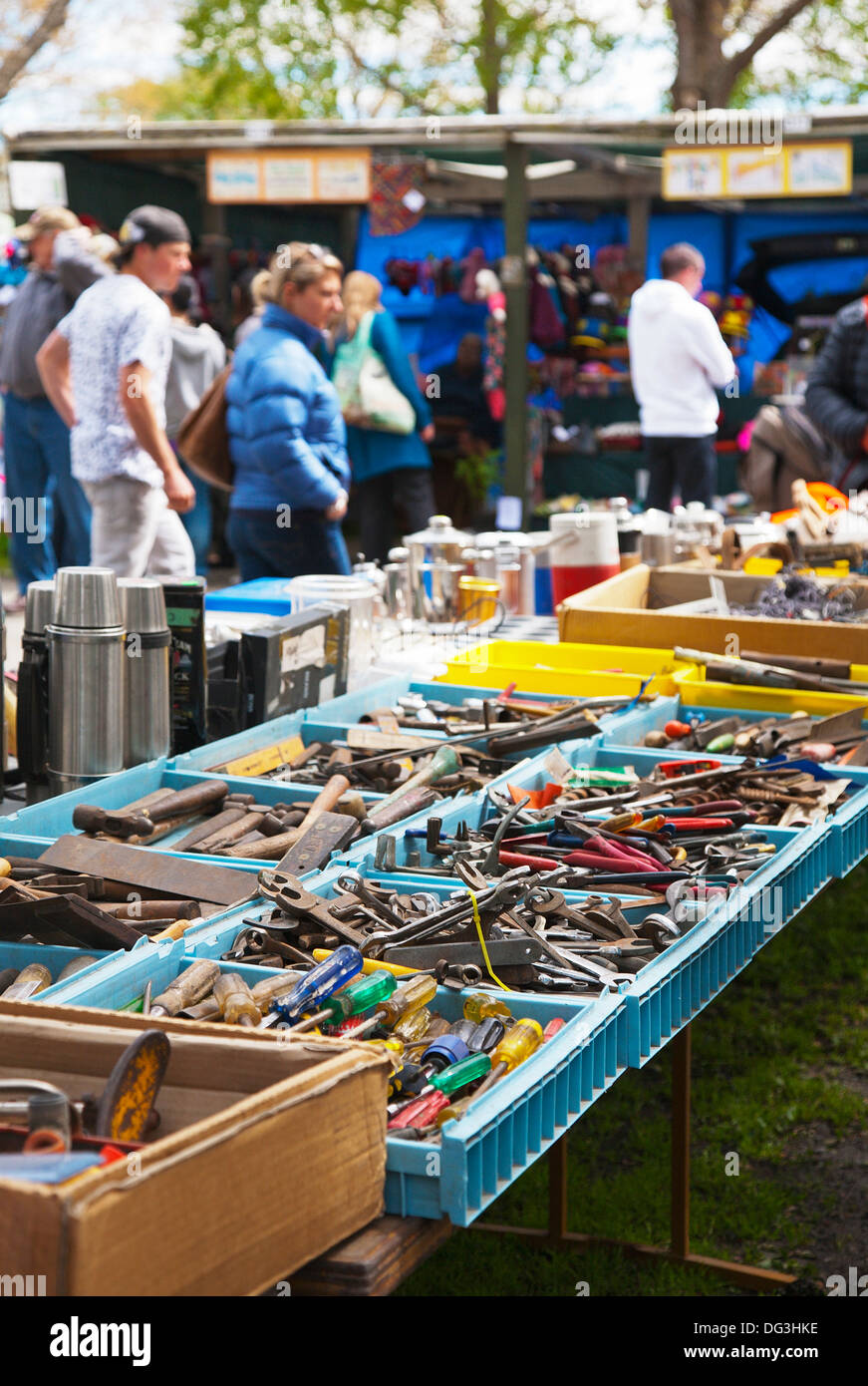 People wandering around stalls selling various used secondhand tools, household equipment and bric-a-brac at an outdoor market. Stock Photo