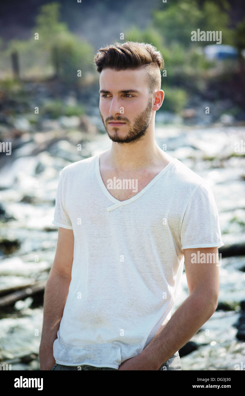 Portrait of handsome young man in white t-shirt outdoors, looking to a ...
