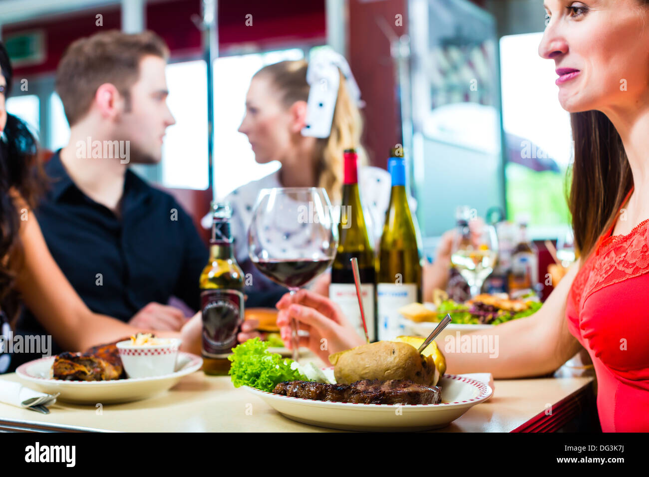 Friends or couples eating fast food and drinking beer and wine in a