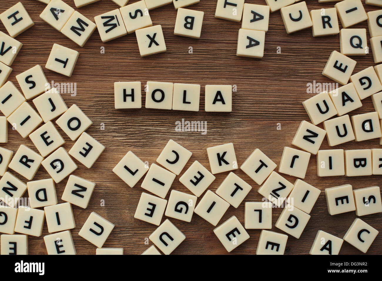 Plastic letters from a childrens' spelling game on a wooden table spell 'hola' Stock Photo