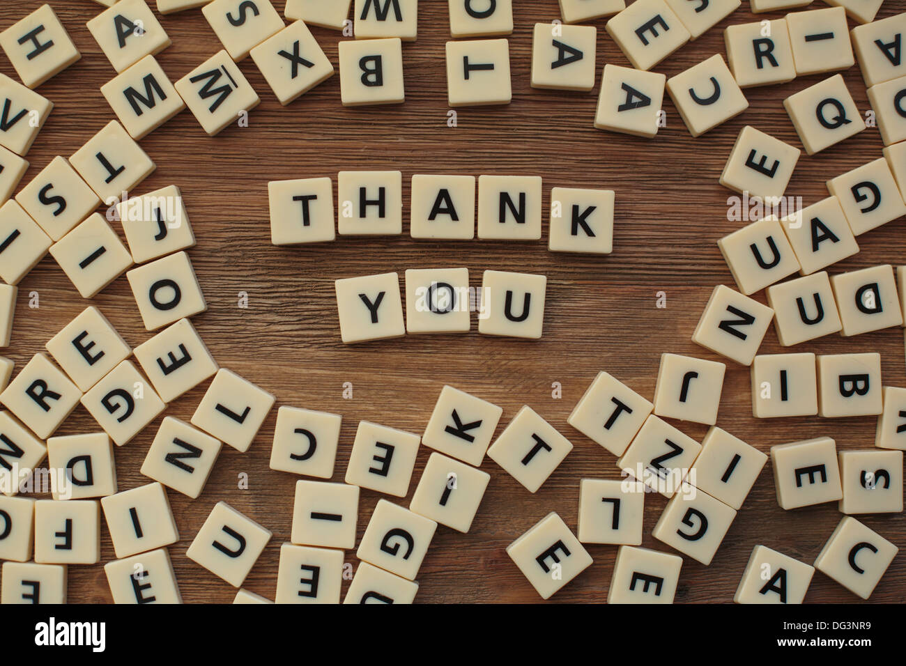 Plastic letters from a childrens' spelling game on a wooden table spell 'thank you' Stock Photo