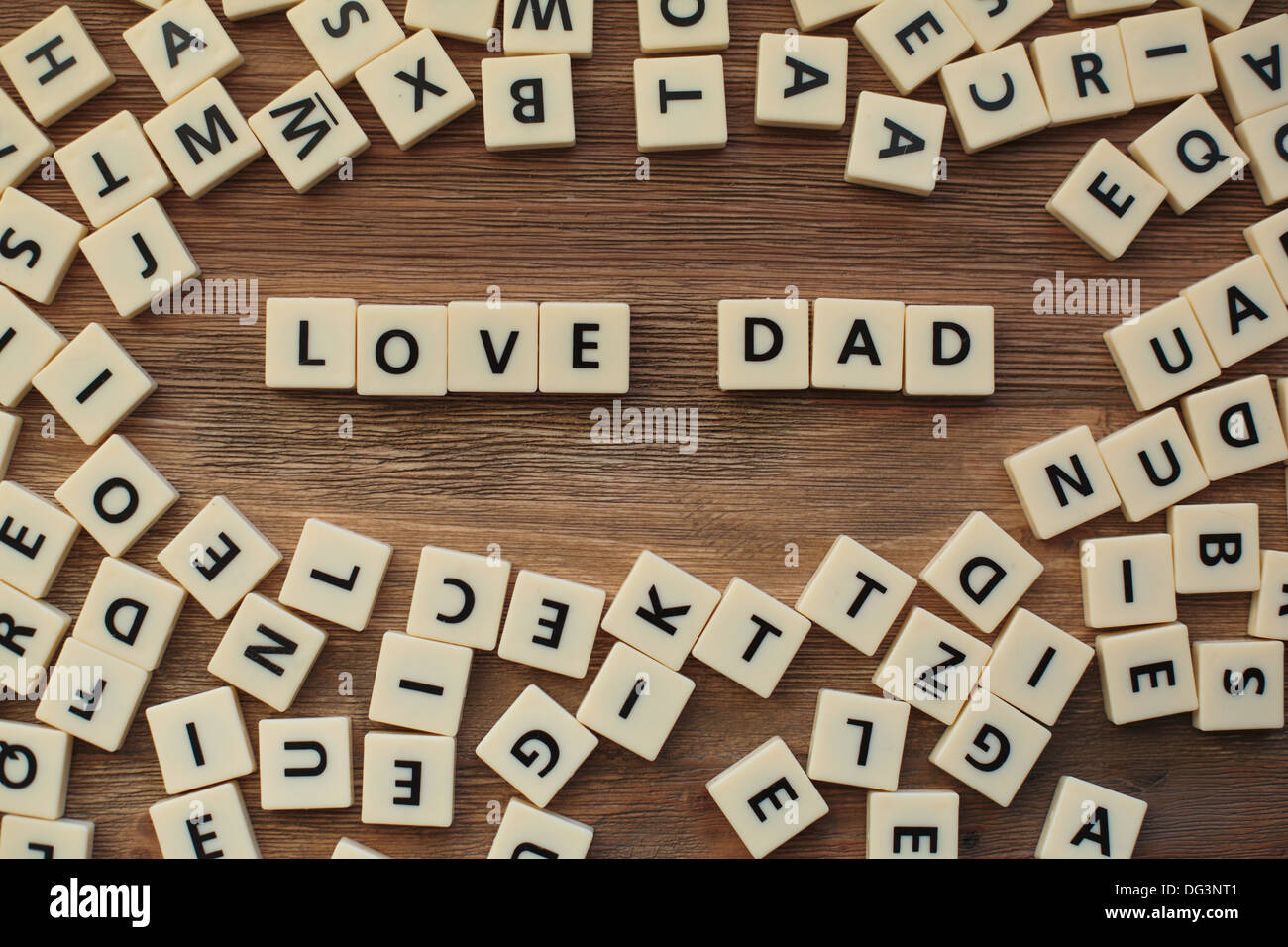 Plastic letters from a childrens' spelling game on a wooden table spell 'Love Dad' Stock Photo
