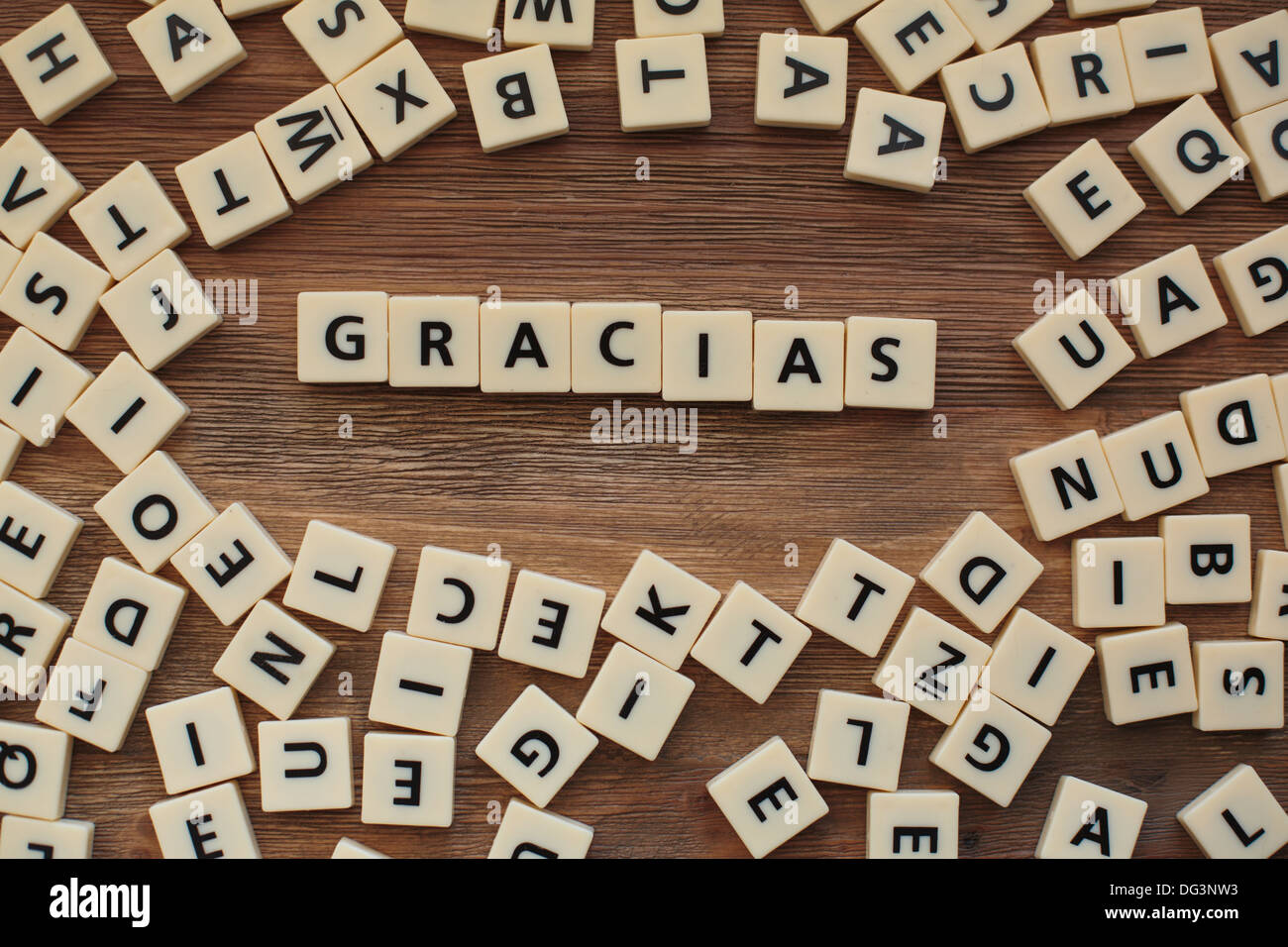 Plastic letters from a childrens' spelling game on a wooden table spell 'Gracias' Stock Photo