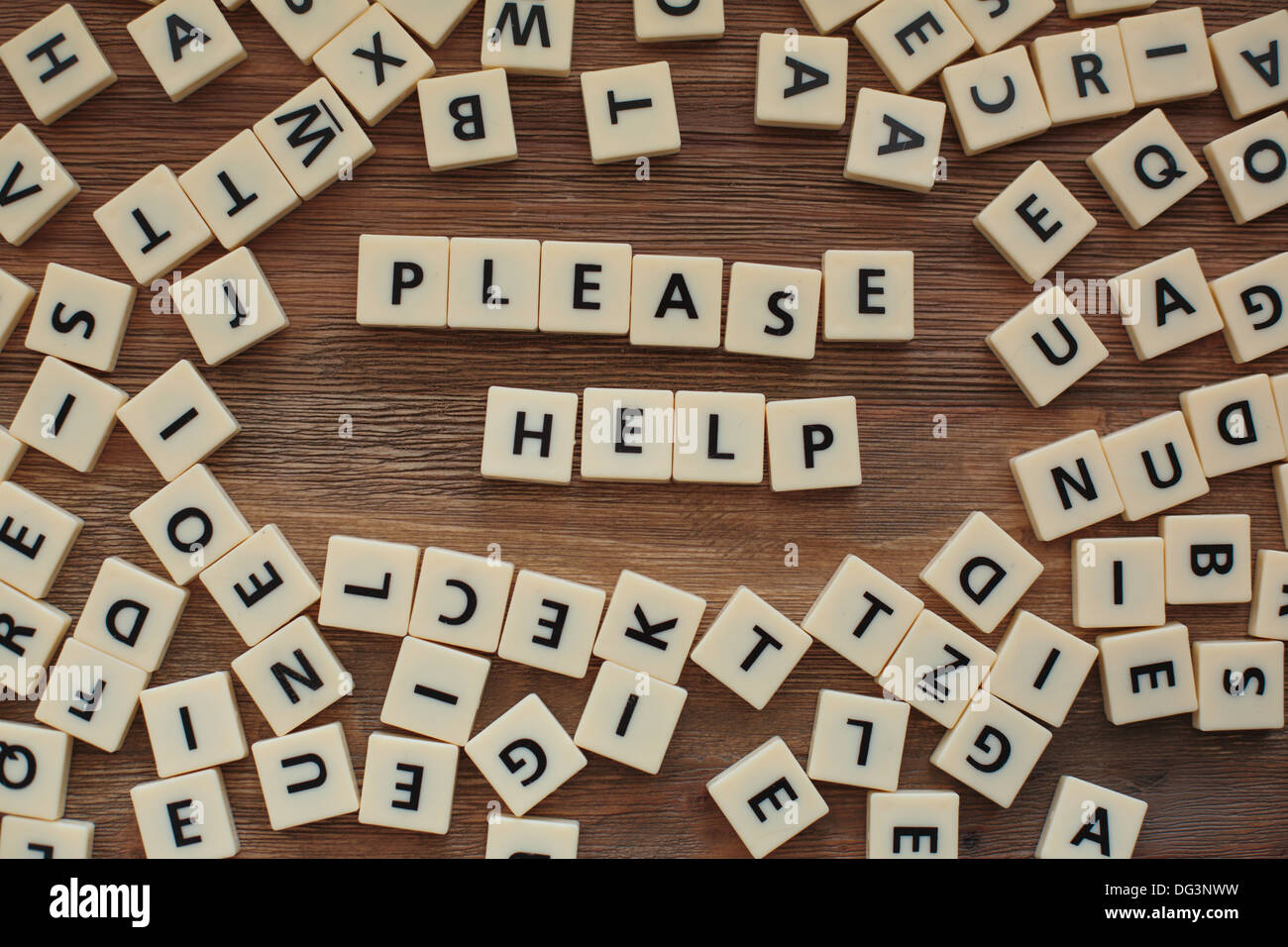 Plastic letters from a childrens' spelling game on a wooden table spell 'please help' Stock Photo