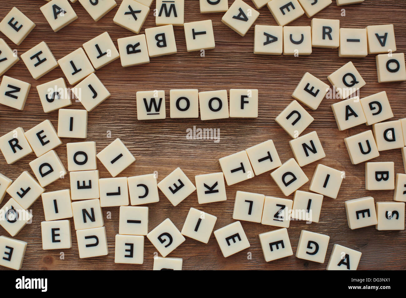 Plastic letters from a childrens' spelling game on a wooden table spell 'Woof' Stock Photo