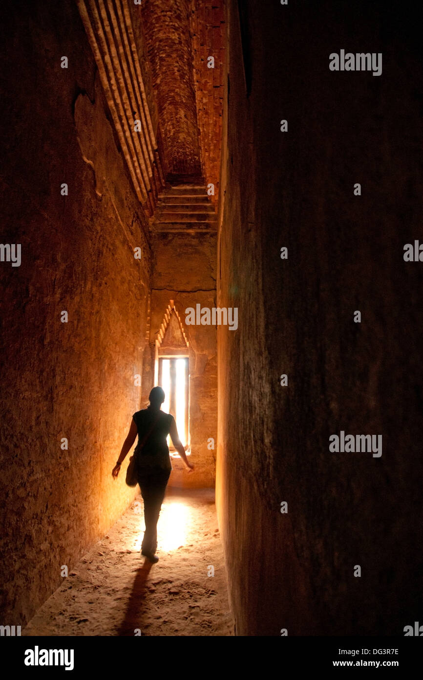 Silhouette of woman walking toward narrow window in a dark ancient temple Stock Photo