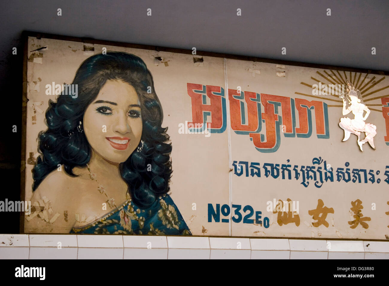 A painted sign showing a woman and written in Khmer and Chinese hangs above a beauty salon  in Phnom Penh, Cambodia. Stock Photo