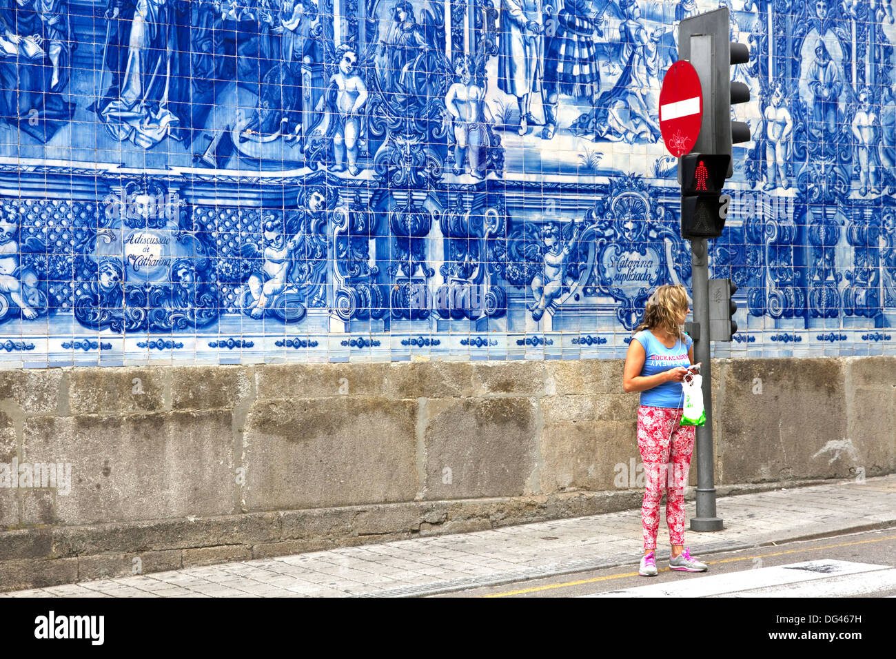 Young woman in front of blue azulejo tiling covering wall of Capela das Almas, town centre, Porto, Portugal Stock Photo