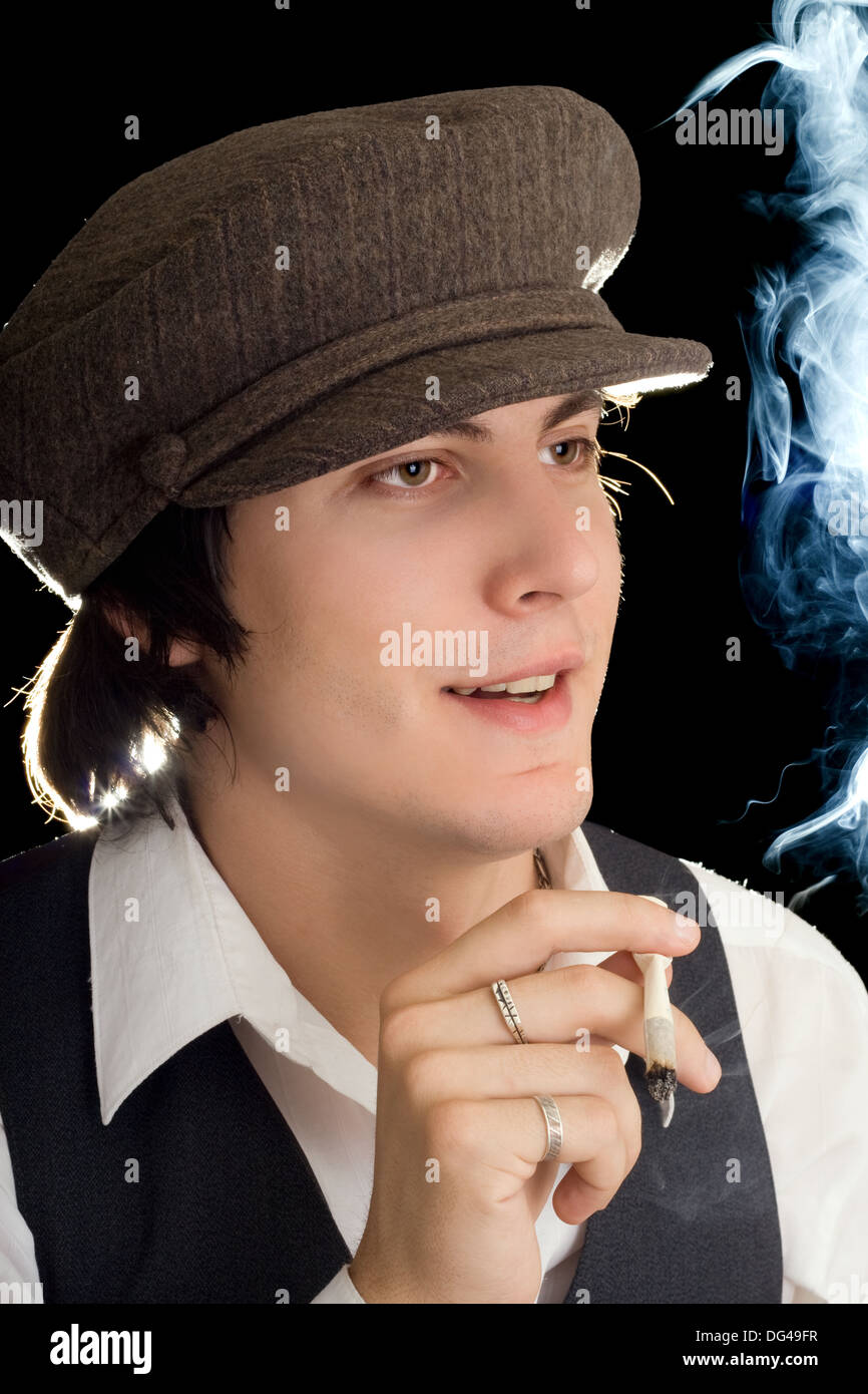 Young man holding a cigarette and looking forward. Isolated Stock Photo